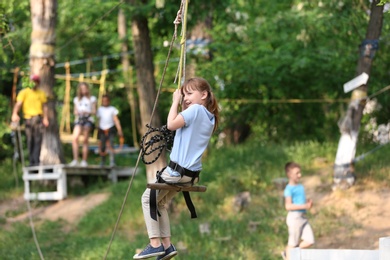 Photo of Little girl on zip line in adventure park. Summer camp