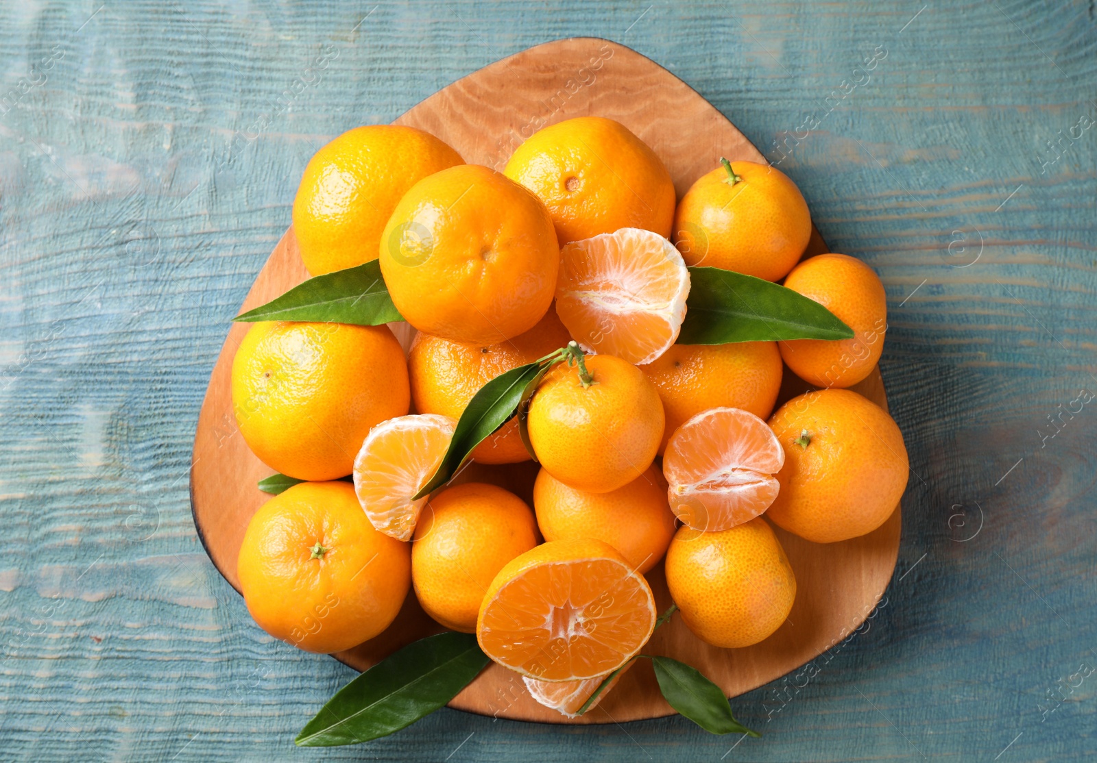 Photo of Fresh ripe tangerines on blue wooden table, top view