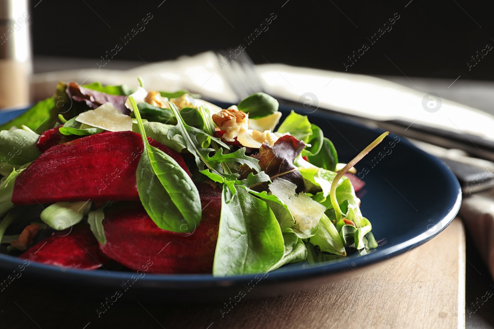 Photo of Plate with delicious beet salad on wooden board, closeup