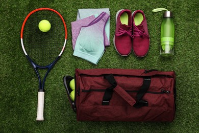 Gym bag and sports equipment on green grass, flat lay