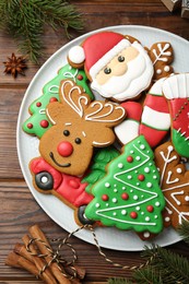 Different tasty Christmas cookies, spices and fir tree branch on wooden table, flat lay