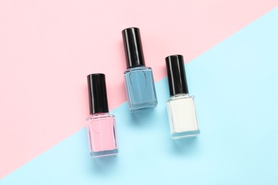 Photo of Bright nail polishes in bottles on color background, flat lay