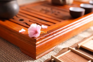 Photo of Tray for traditional tea ceremony with sakura flower on table, closeup