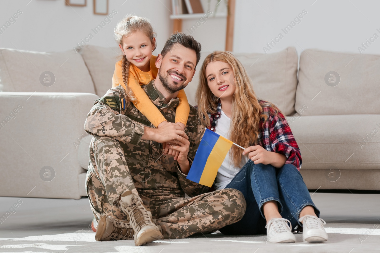 Photo of Soldier in military uniform reunited with his family and Ukrainian flag on floor at home