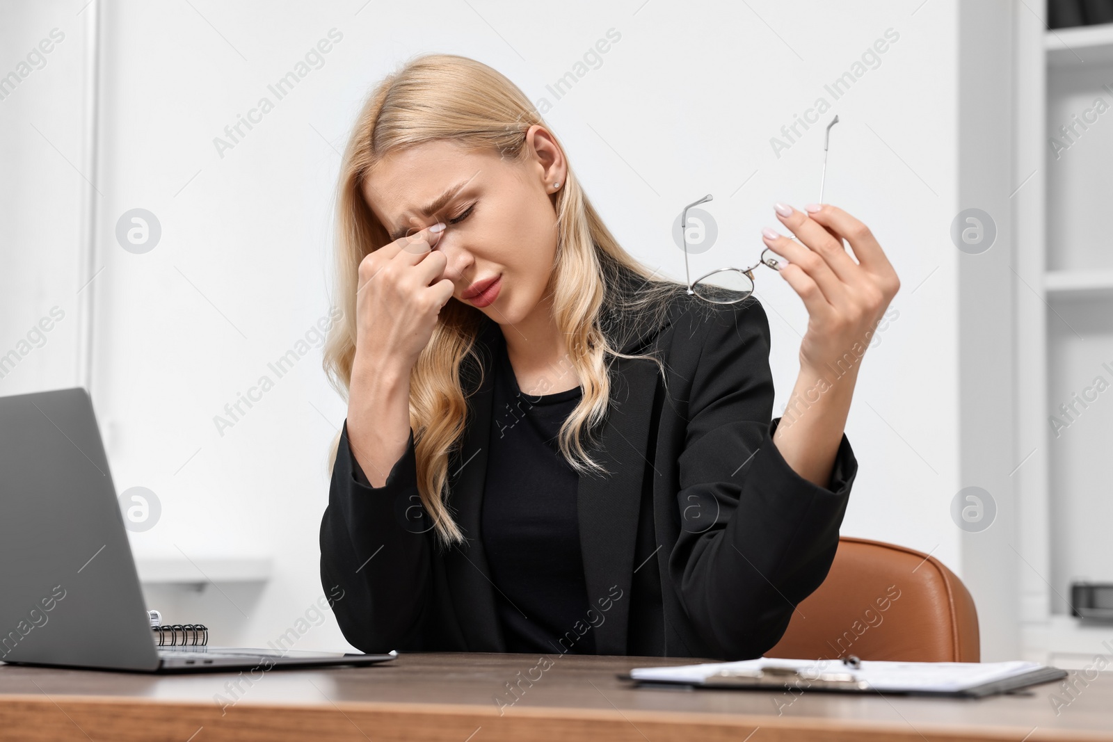 Photo of Overwhelmed woman with glasses at wooden table in office