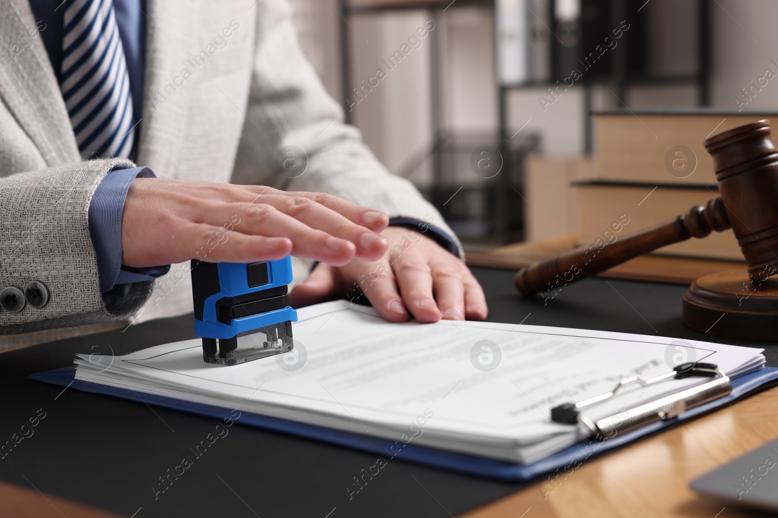 Photo of Notary stamping document at table in office, closeup