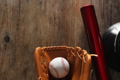 Photo of Baseball glove, bat, ball and batting helmet on wooden table, flat lay. Space for text