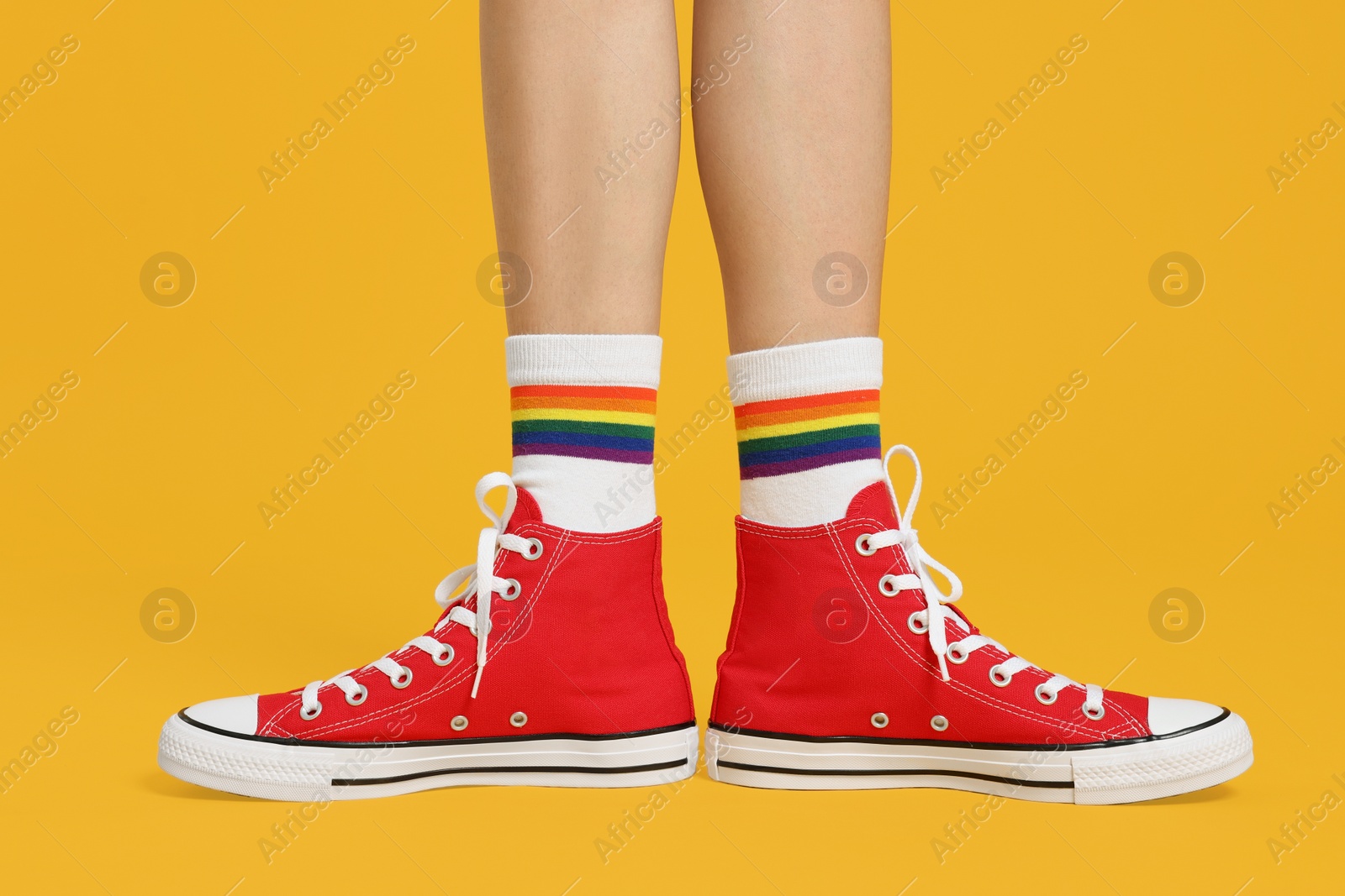 Photo of Woman in stylish gumshoes on yellow background, closeup