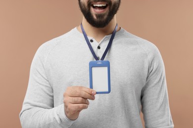 Man with blank badge on beige background, closeup