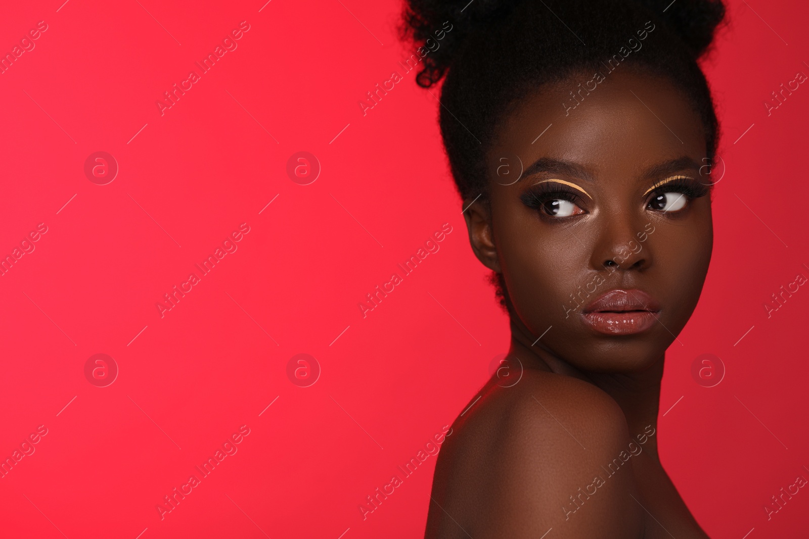 Photo of Fashionable portrait of beautiful woman with bright makeup on coral background, space for text