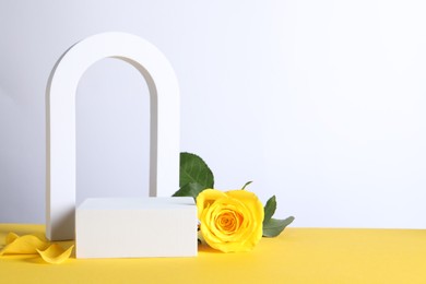 Beautiful presentation for product. Geometric figures and rose on yellow table against white background, space for text