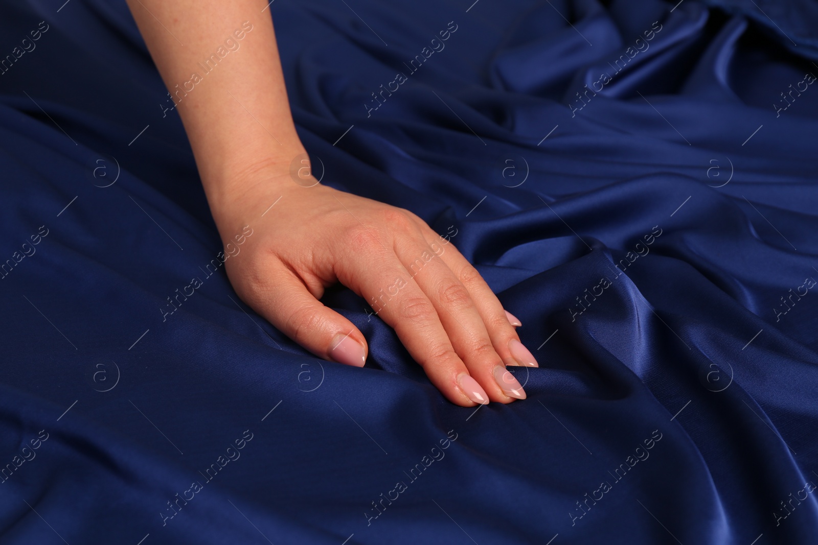 Photo of Woman touching silky blue fabric, closeup view