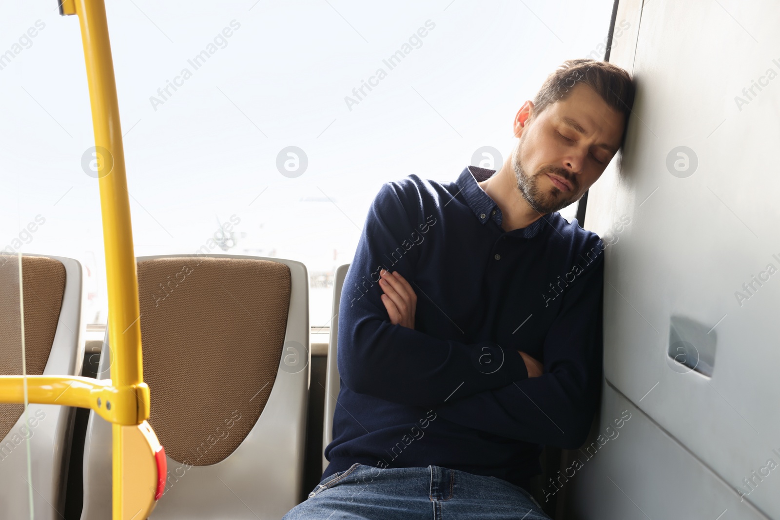 Photo of Tired man sleeping while sitting in public transport