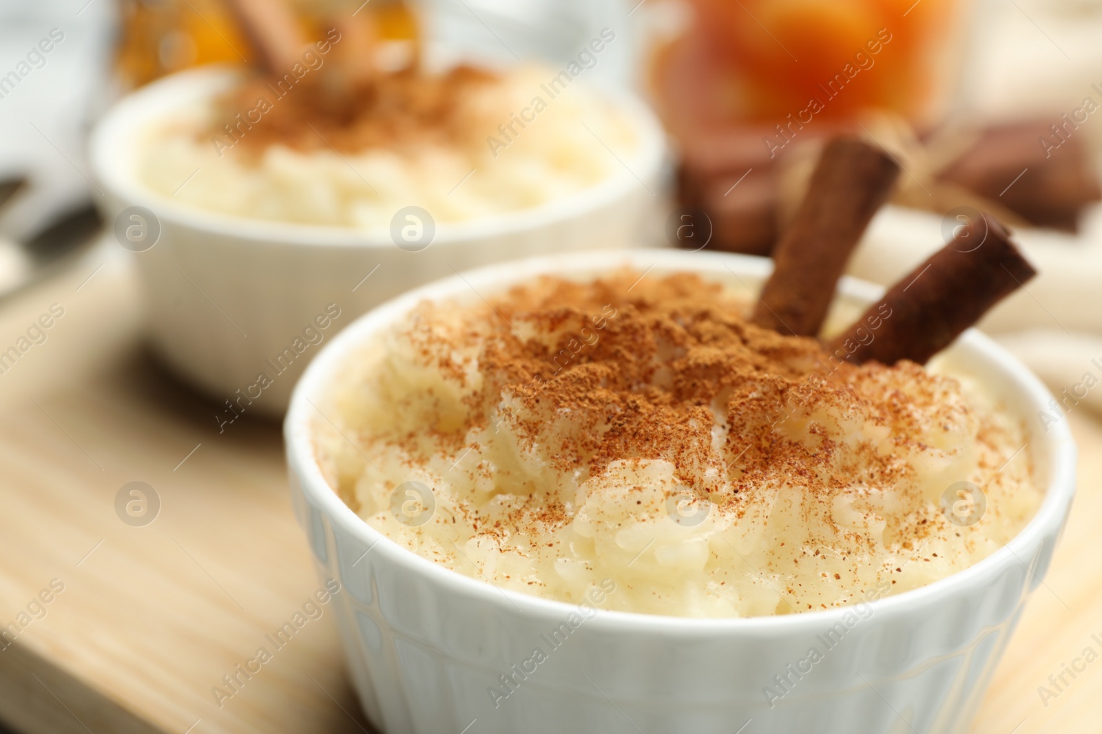 Photo of Delicious rice pudding with cinnamon on wooden board, closeup