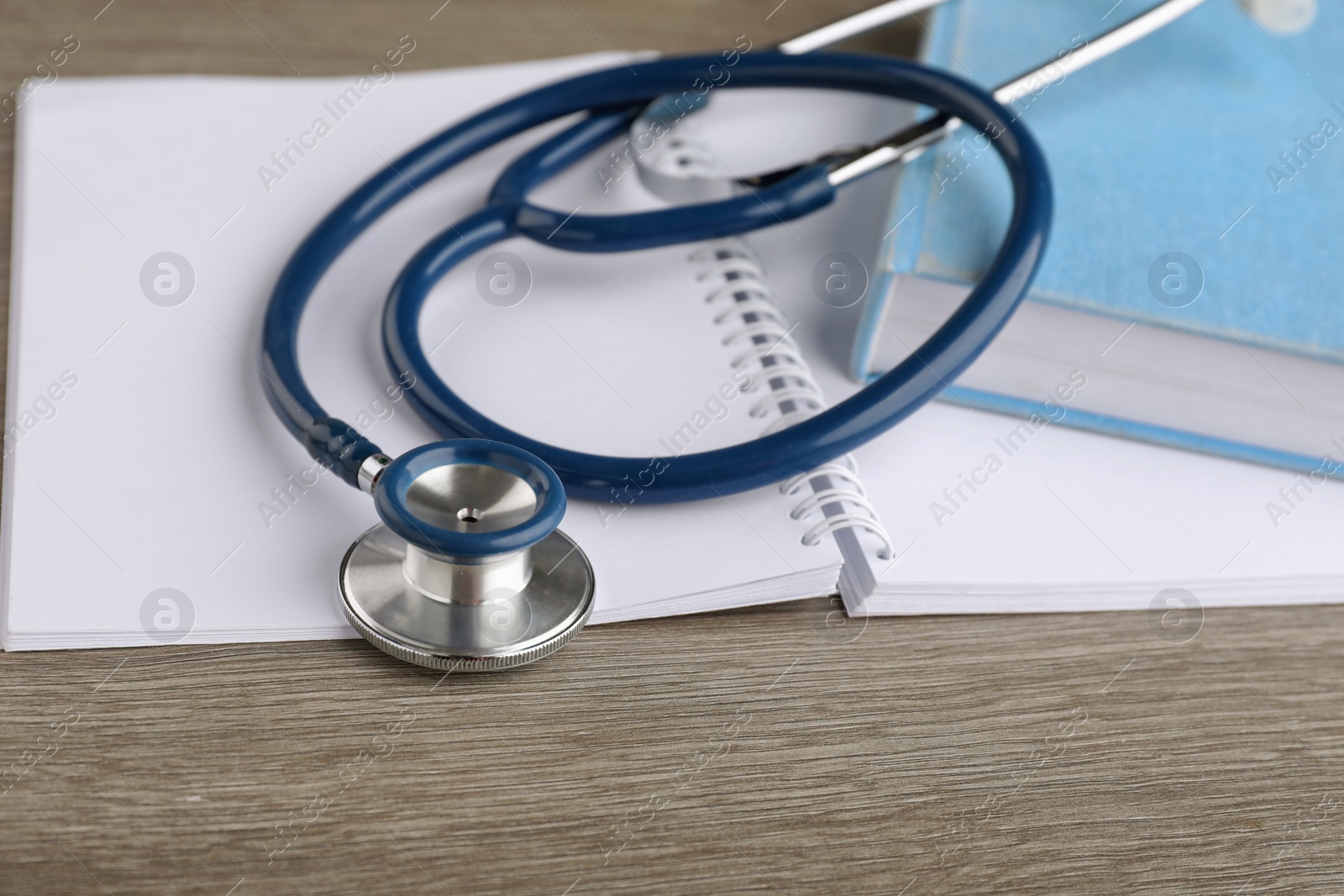 Photo of Book, stethoscope and notebook on wooden table, closeup. Medical education