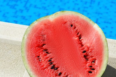 Photo of Half of fresh juicy watermelon near swimming pool outdoors, top view