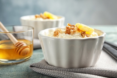 Creamy rice pudding with walnuts and orange slice in ramekin on table