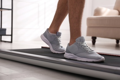 Man training on walking treadmill at home, closeup
