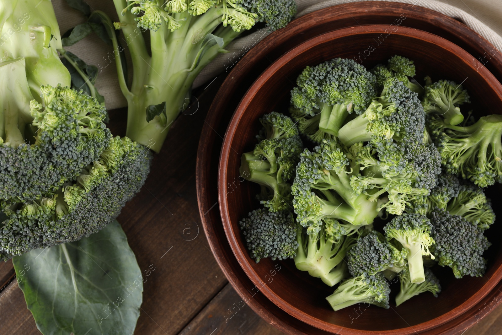 Photo of Bowl with fresh raw broccoli on wooden table, flat lay