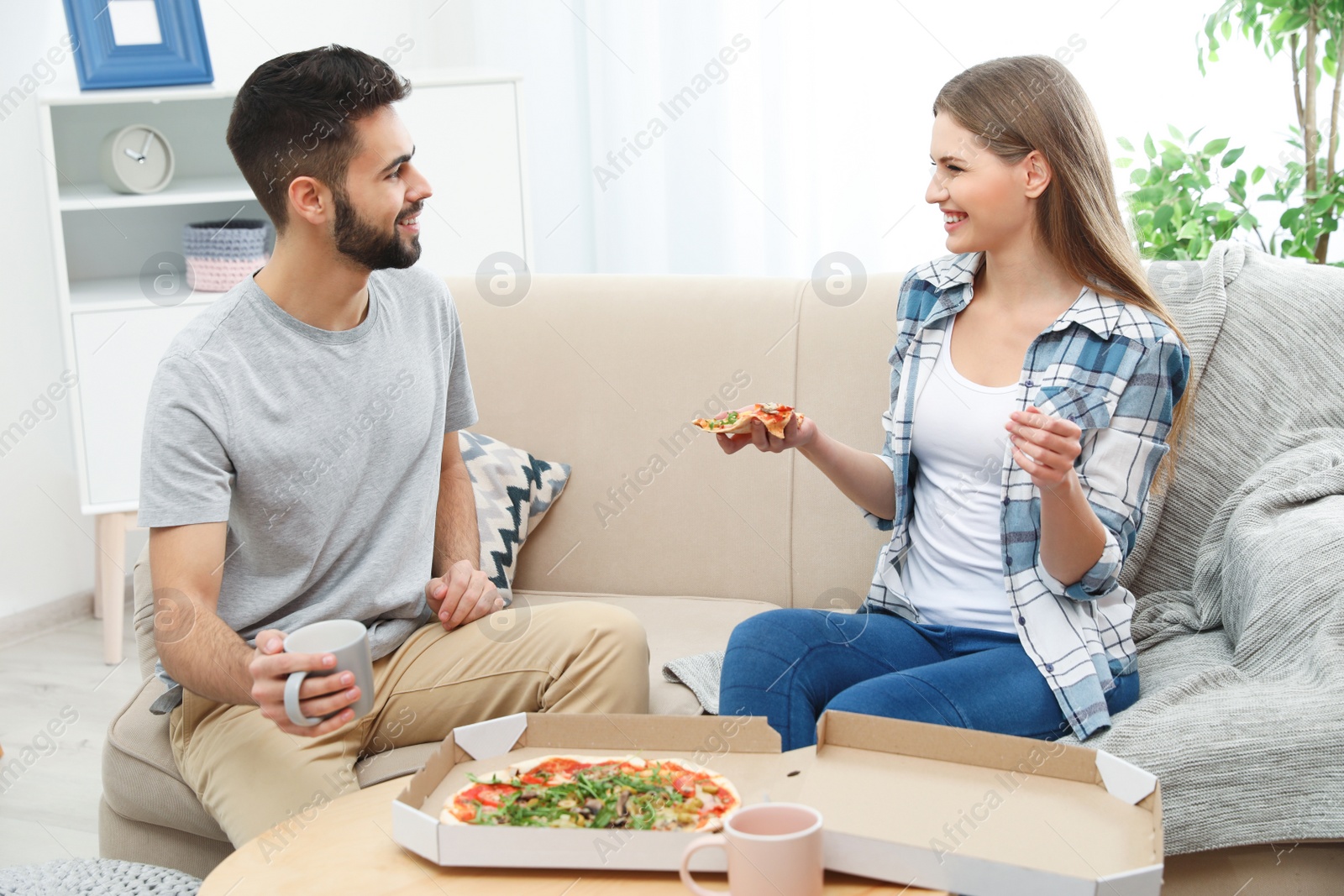 Photo of Young couple having pizza for lunch in living room. Food delivery