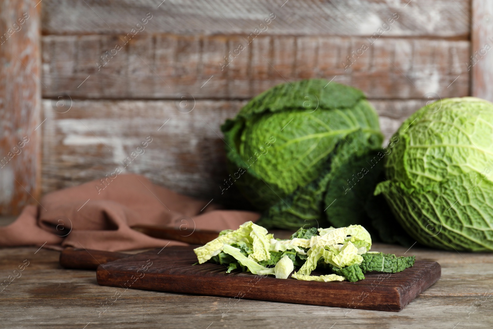 Photo of Cutting board with chopped savoy cabbage on wooden table