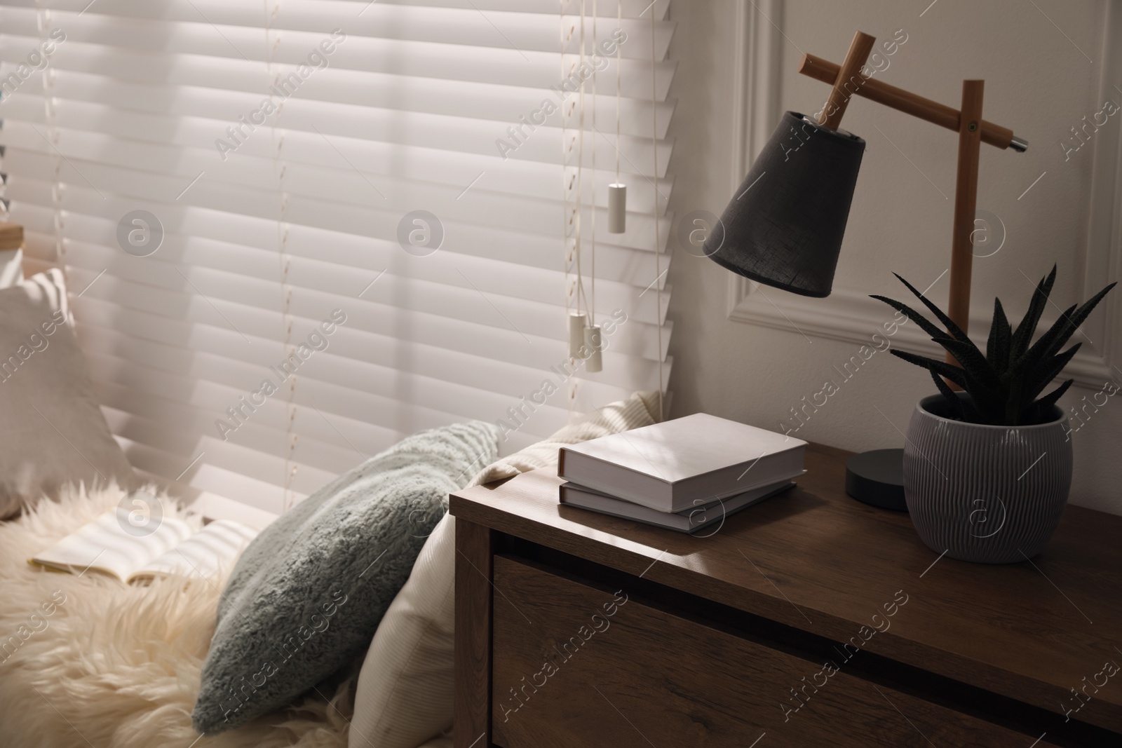 Photo of Comfortable place for relax with faux fur and pillows near window in room