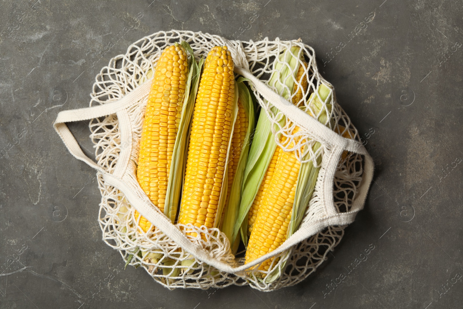 Photo of Bag of corn cobs on grey table, top view