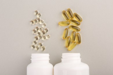 Photo of Bottles and different vitamin capsules on light grey background, flat lay