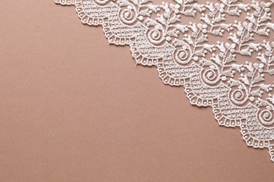 Photo of White lace on beige background, top view. Space for text