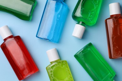 Fresh mouthwashes in bottles on light blue background, flat lay