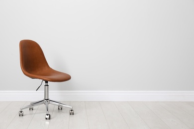 Photo of Comfortable office chair near light wall indoors. Space for text