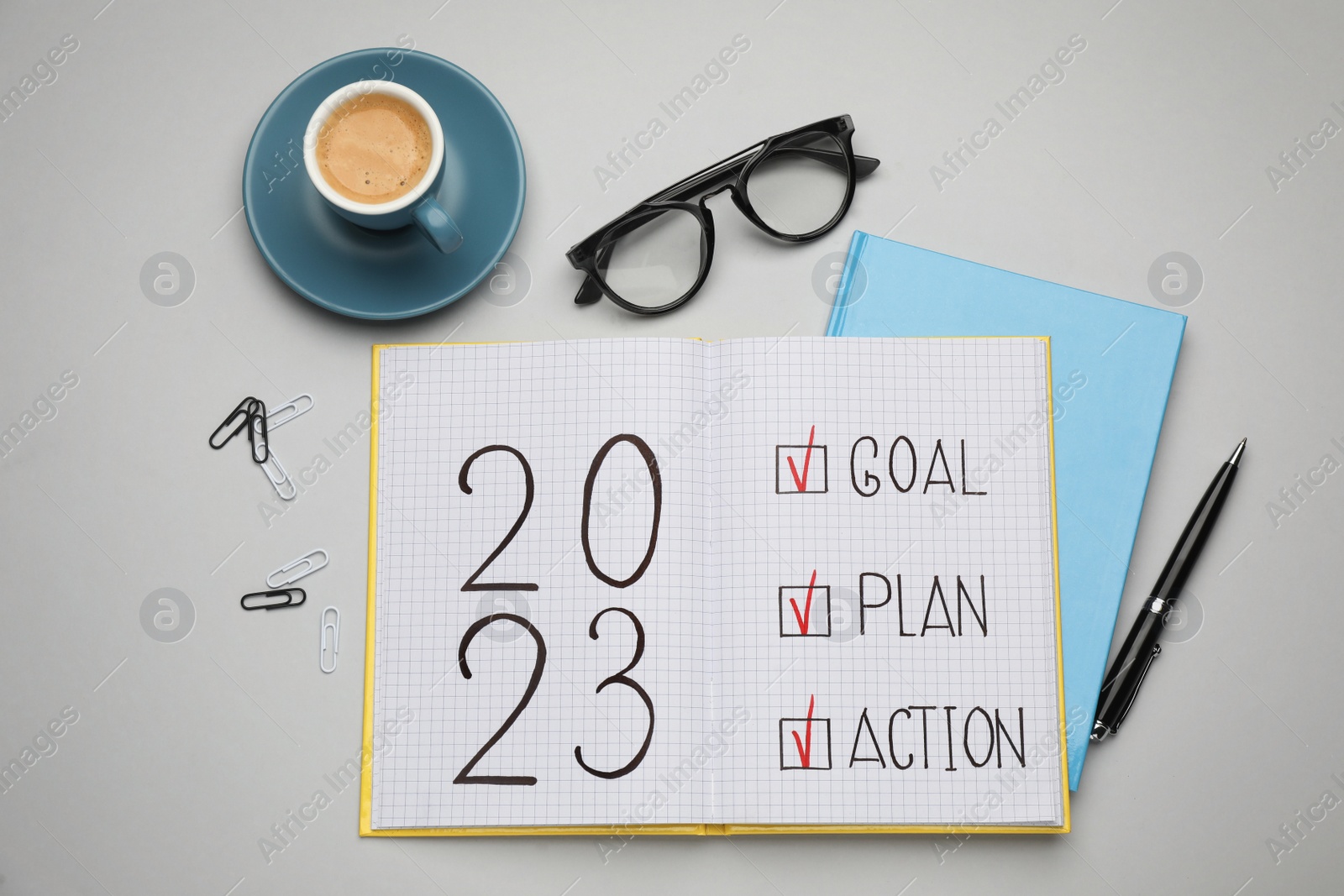 Photo of Flat lay composition of notebook with text 2023 Goal, Plan, Action on light grey background. New year resolutions