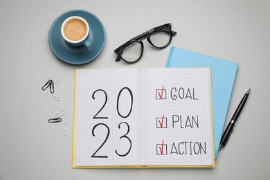Photo of Flat lay composition of notebook with text 2023 Goal, Plan, Action on light grey background. New year resolutions