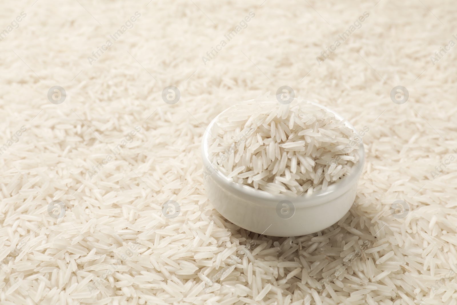 Photo of Bowl on raw basmati rice, closeup view. Space for text