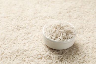 Photo of Bowl on raw basmati rice, closeup view. Space for text