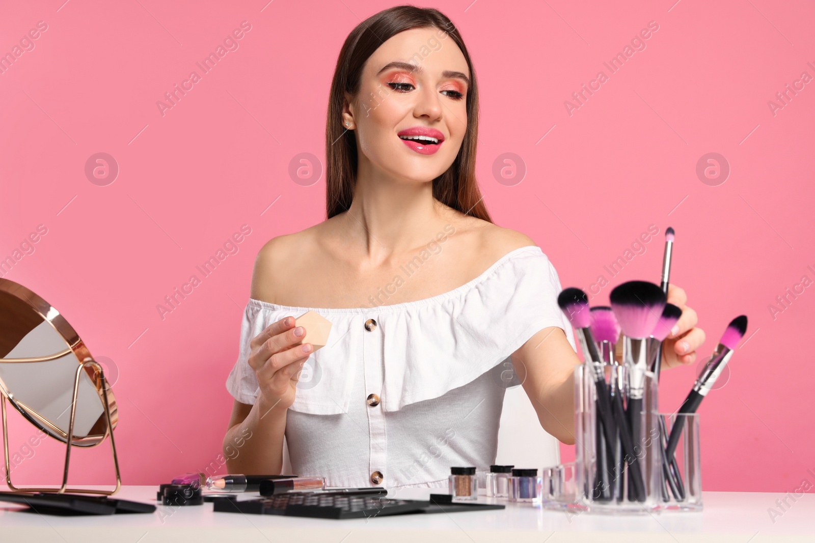 Photo of Beauty blogger with set of makeup brushes on pink background