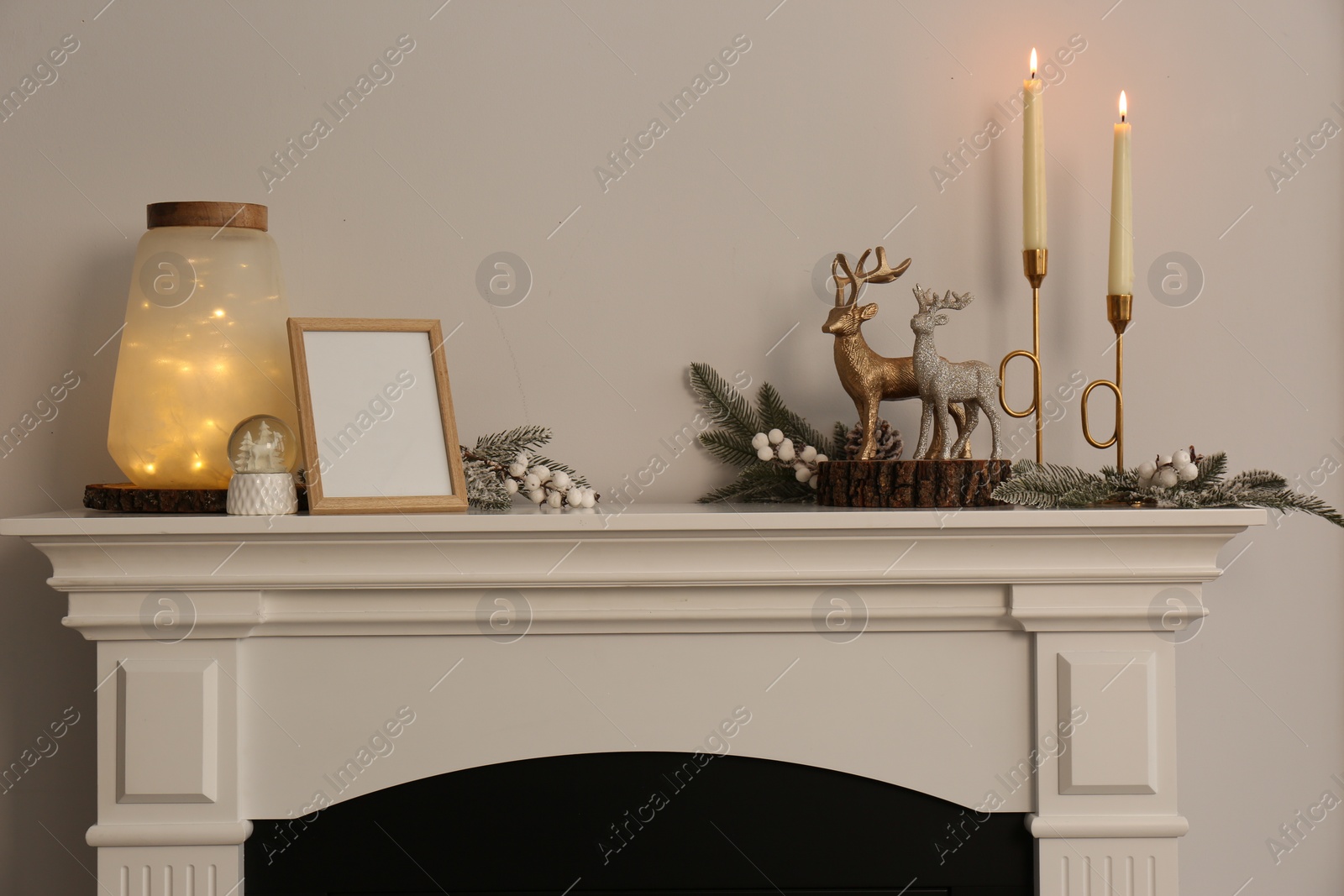 Photo of Stylish interior decorations on fireplace near white wall indoors