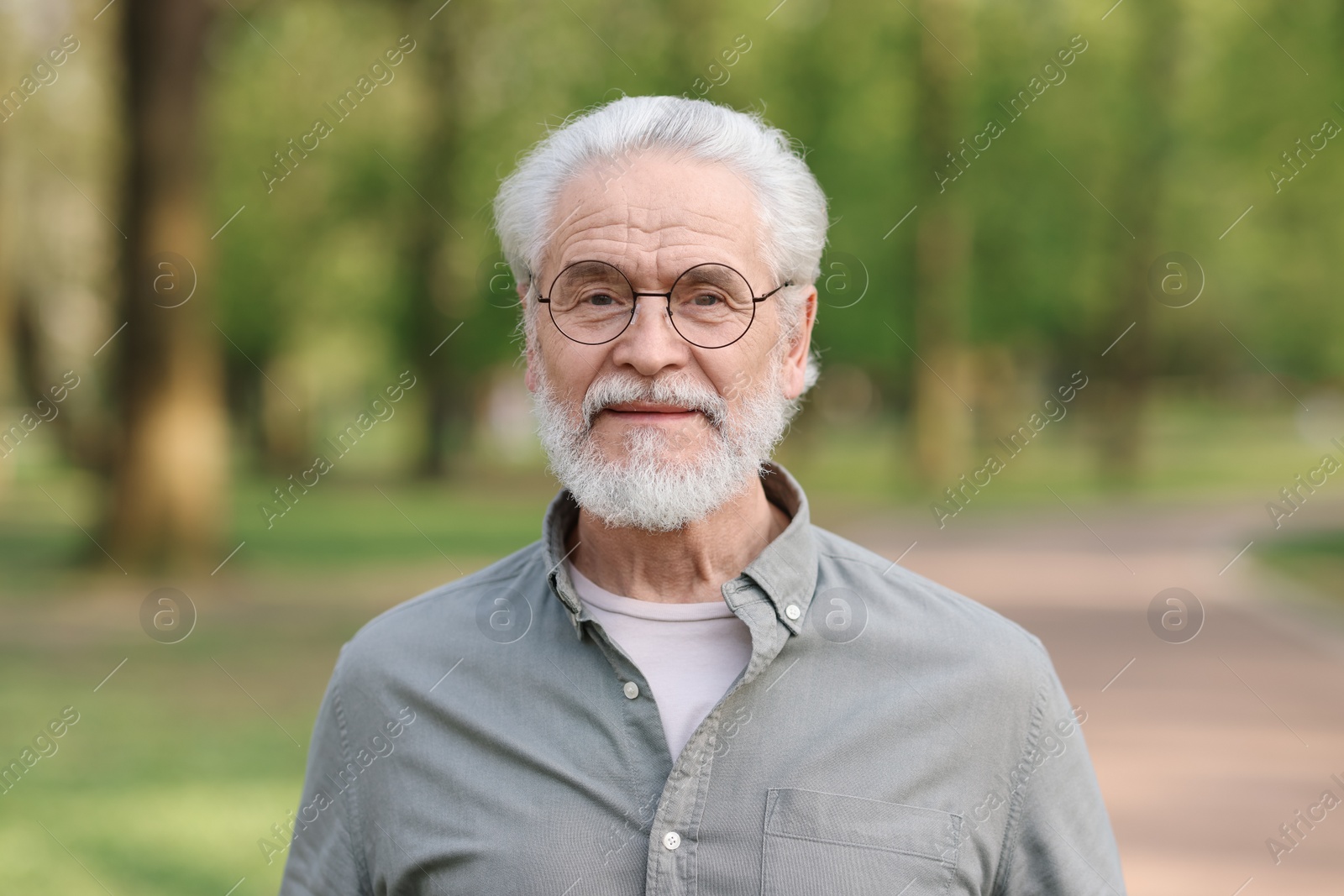 Photo of Portrait of happy grandpa with glasses in park