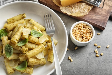 Flat lay composition with plate of delicious basil pesto pasta on gray table