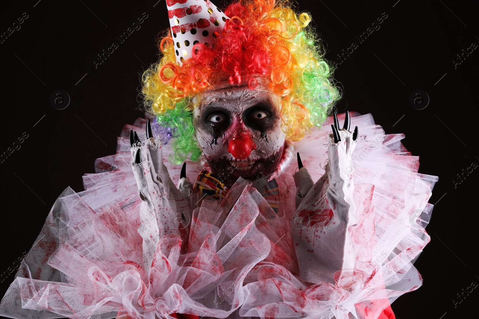 Photo of Terrifying clown on black background. Halloween party costume