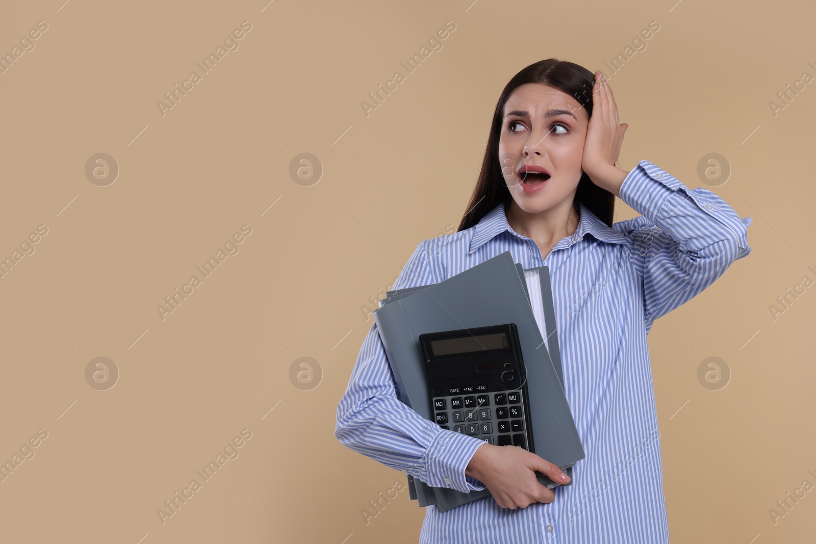 Photo of Emotional accountant with calculator and folders on beige background