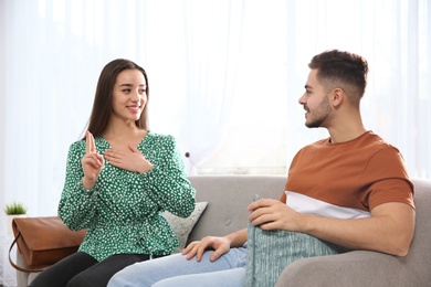 Hearing impaired friends using sign language for communication on sofa in living room