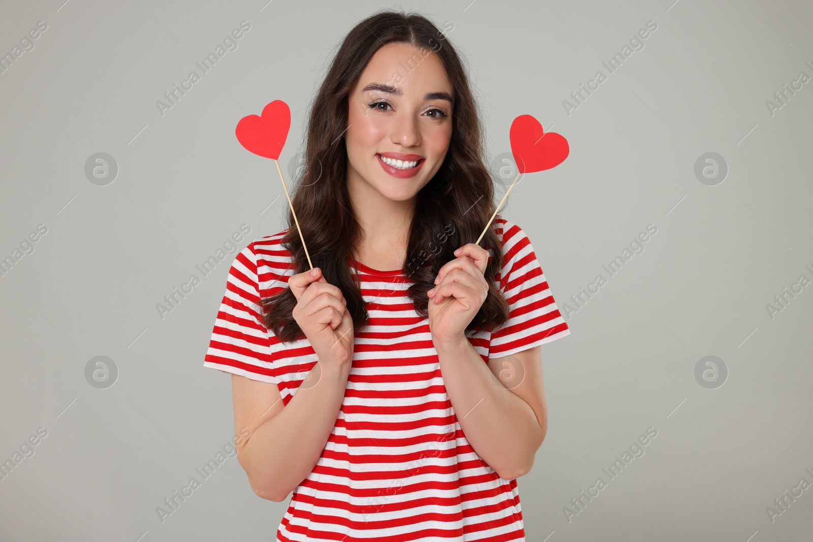 Photo of Beautiful young woman with paper hearts on grey background