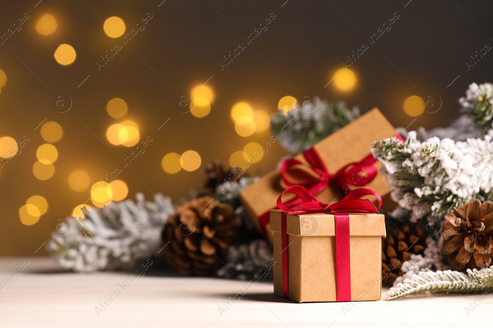 Photo of Gift boxes and Christmas decor on wooden table against blurred festive lights, space for text