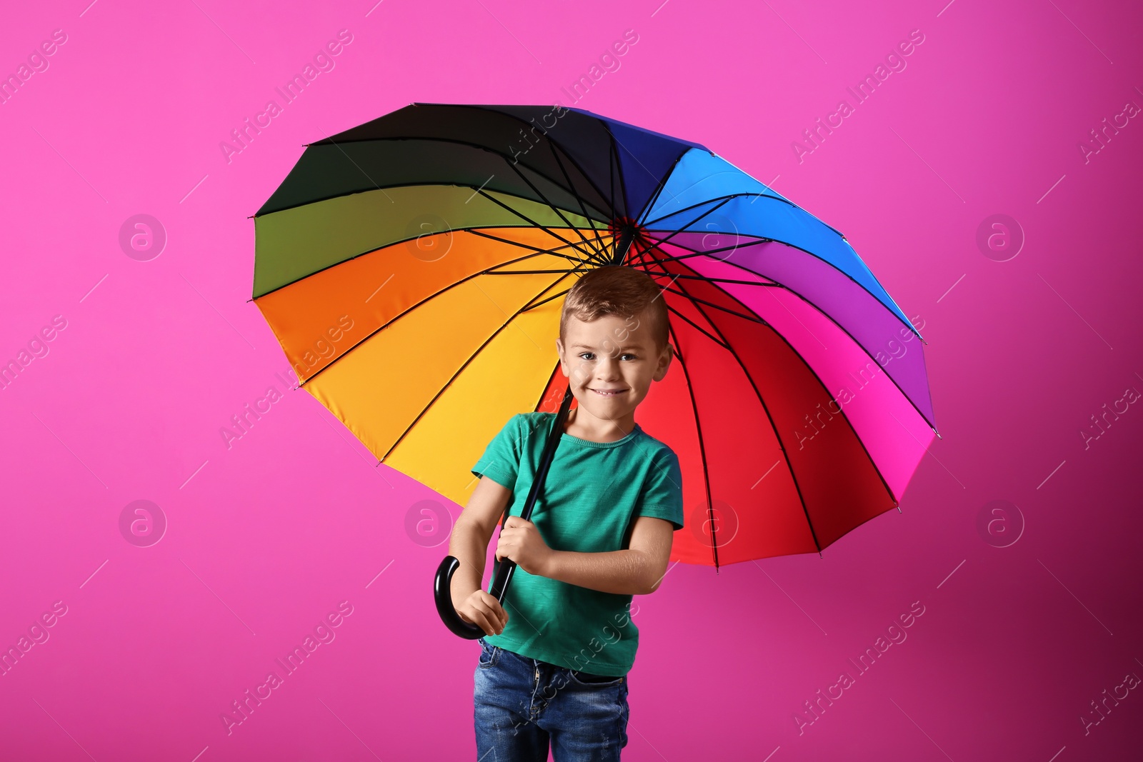 Photo of Little boy with rainbow umbrella on color background