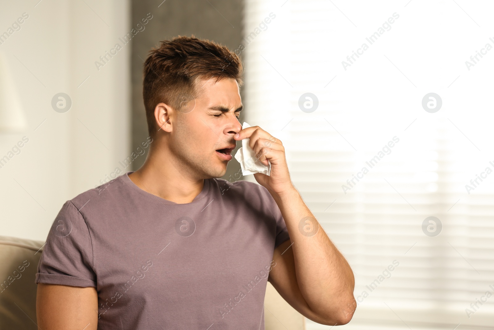 Photo of Young man suffering from allergy at home