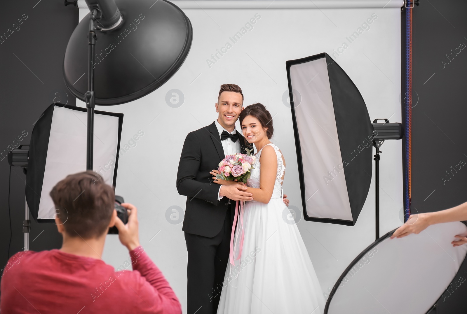 Photo of Professional photographer taking photo of wedding couple in studio