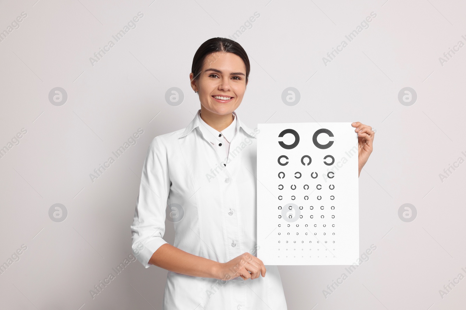 Photo of Ophthalmologist with vision test chart on light background