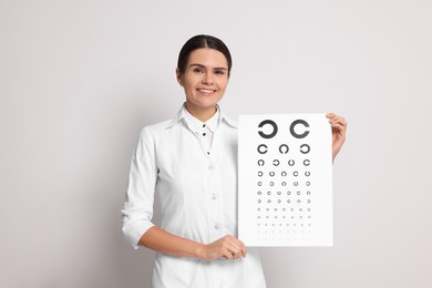 Photo of Ophthalmologist with vision test chart on light background