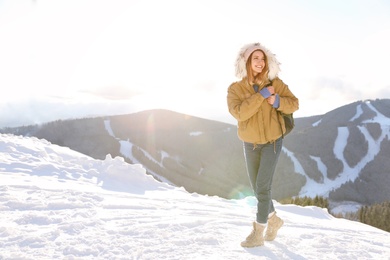 Photo of Happy young woman with backpack spending winter vacation in mountains. Space for text